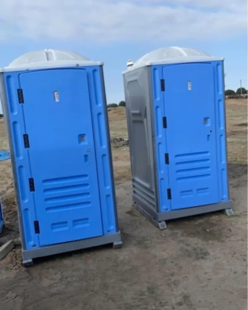 Two portable toilets placed on a graded dirt construction lot