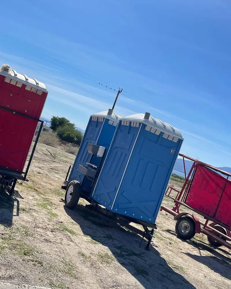 Portable toilet trailer staged on an open rural job site