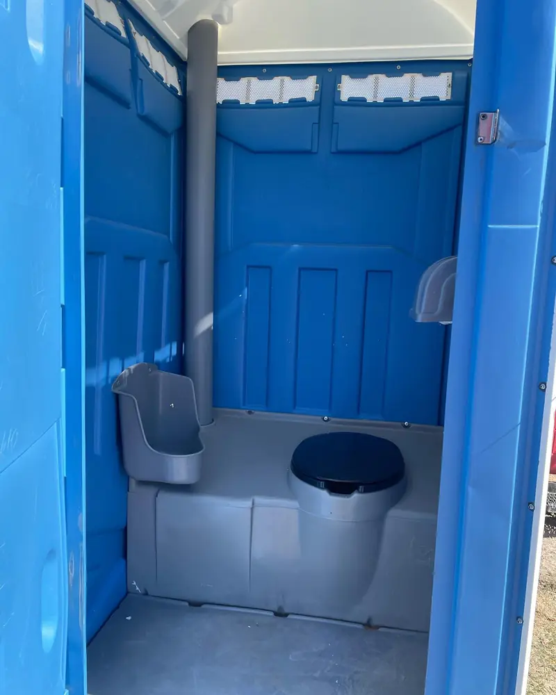 Interior of a standard portable toilet showing the seat, urinal, vent pipe and toilet paper holder